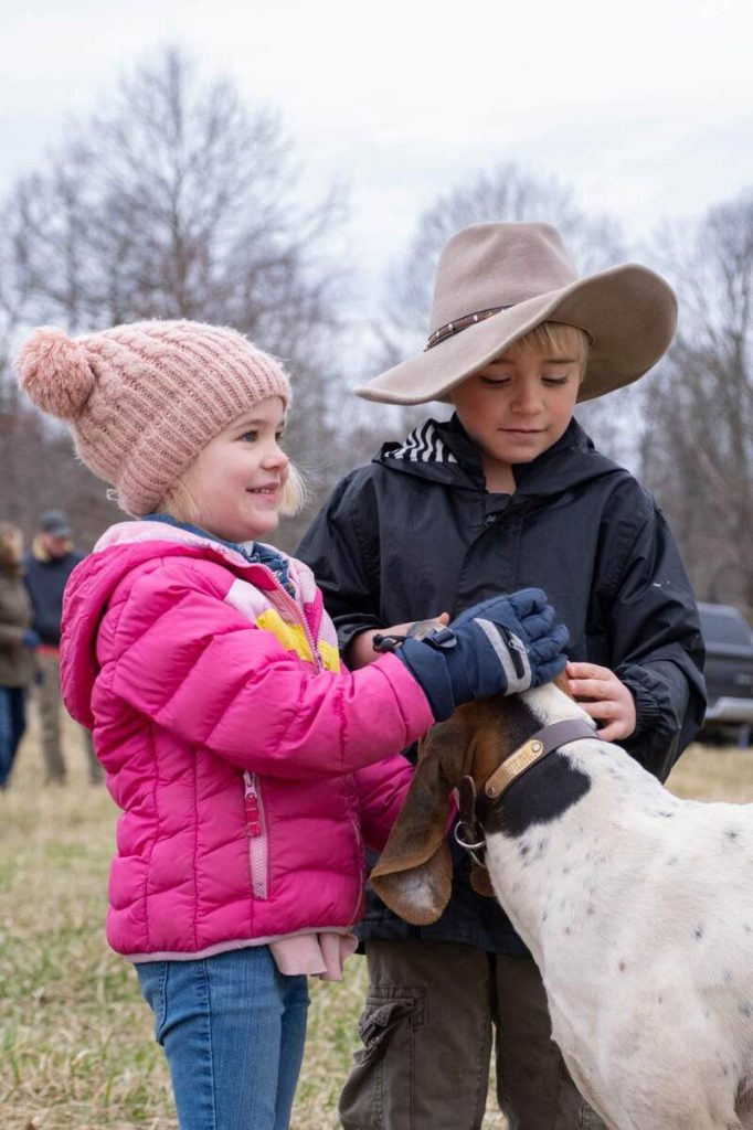 young girl and boy petting foxhound