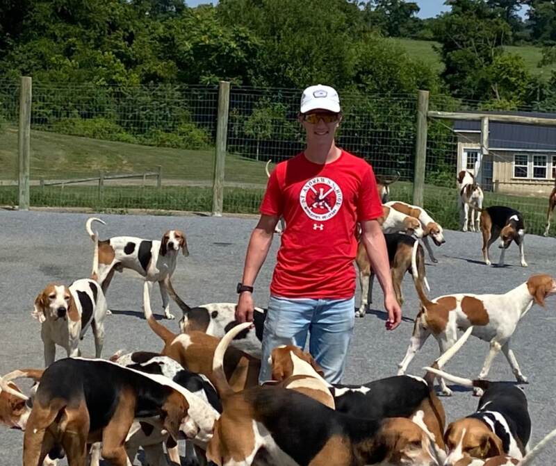 young man with foxhounds in kennel yard