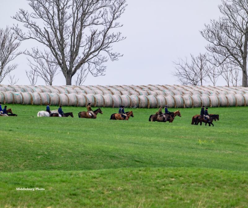 riders going across field by round bales